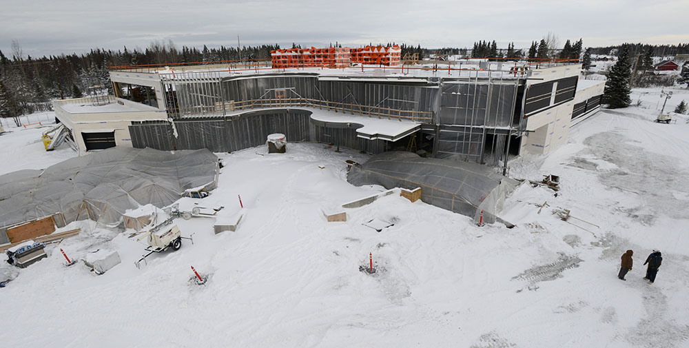 View of the Dena'ina Wellness Center construction show Lobby/Gathering Area in the foreground with 2nd floor curved balcony and roofing insulation staged at the upper roof beyond.